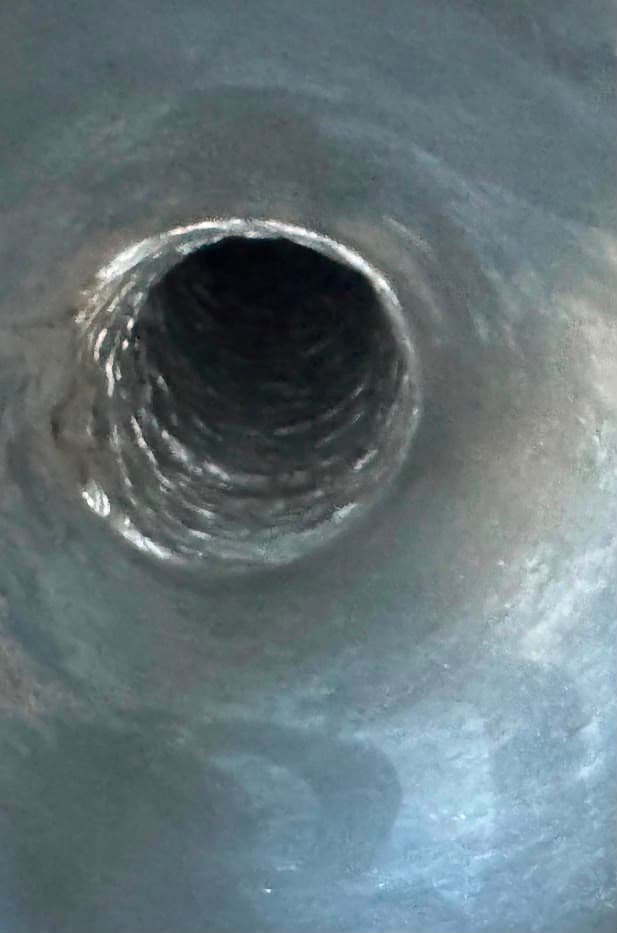 Close-up view looking down the dark, rifled interior of a metallic pipe or barrel.